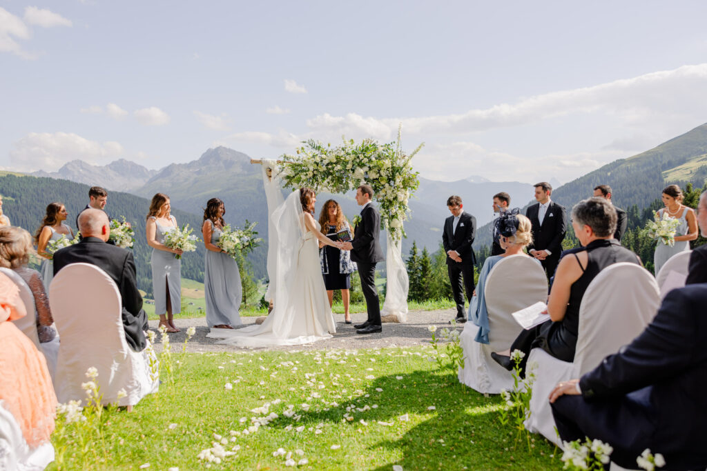Hochzeit auf der Schatzalp Davos 1 Hochzeitszeremonie im Freien mit dem Paar vor dem Altar, den Gästen, den Bergen und dem Grün im Hintergrund - perfekt für alle, die von einer Hochzeit im Ausland träumen.