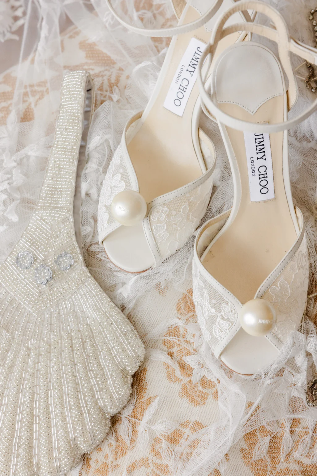Wedding Photography South France 18 White Jimmy Choo lace wedding shoes with pearl embellishments next to a clutch with pearl embroidery.