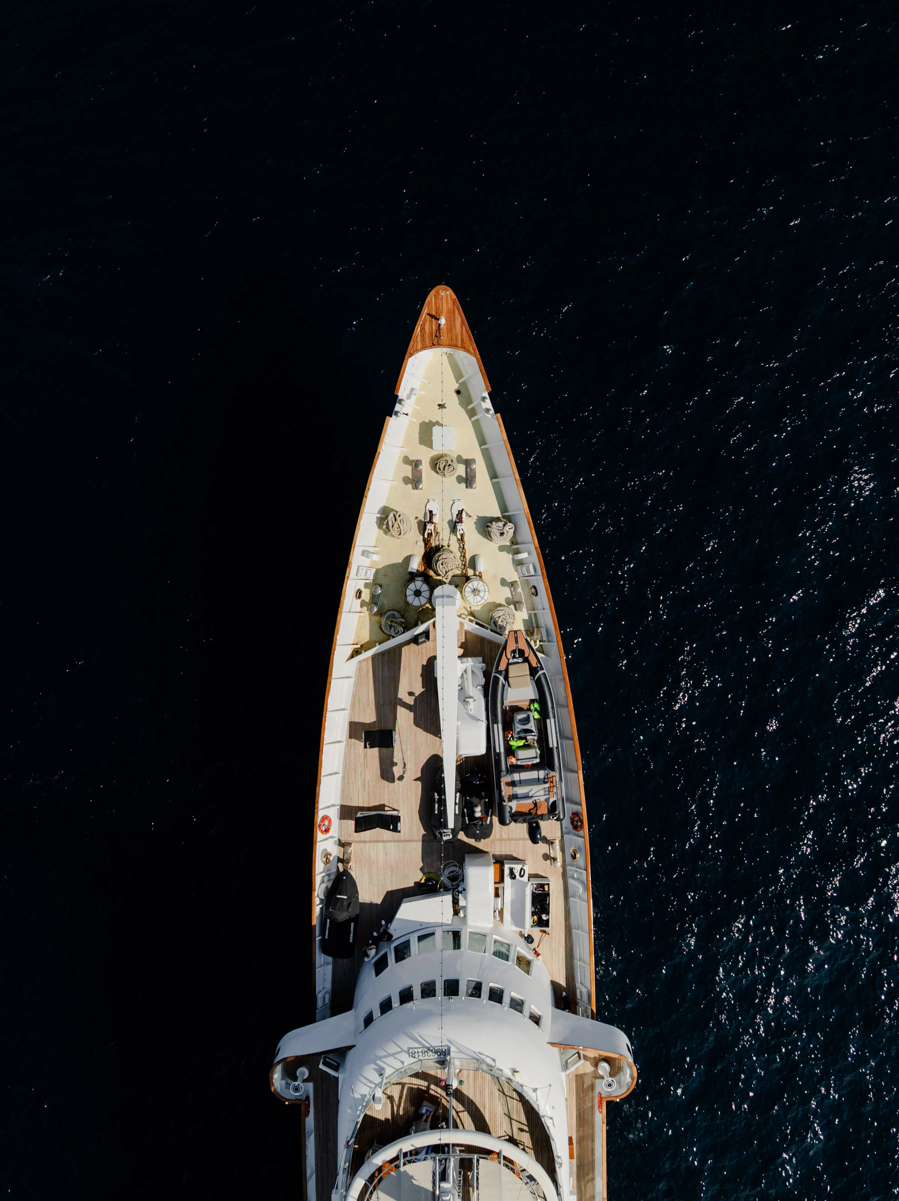 Aerial view of the bug of a yacht on dark water.