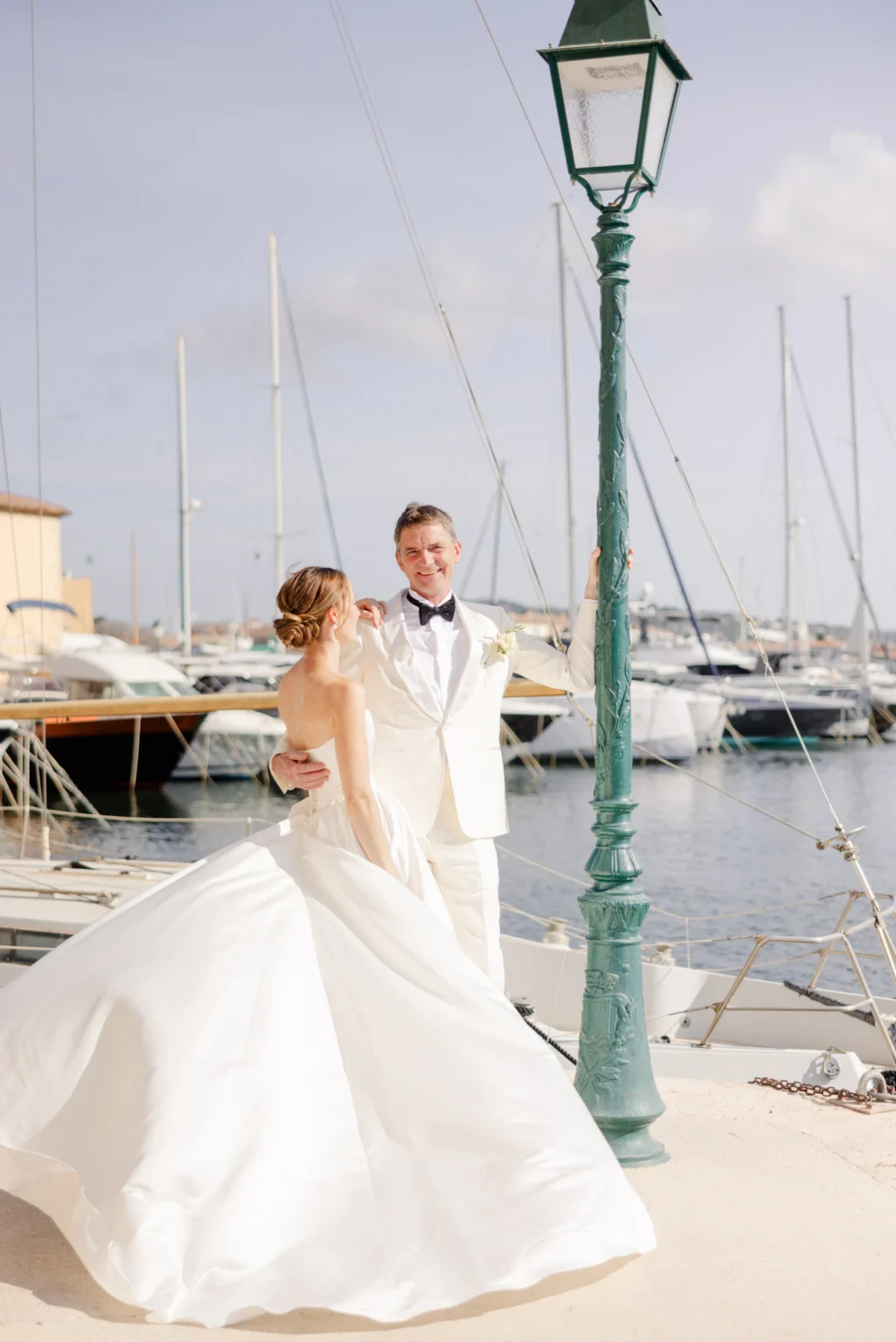 Wedding Photography South France 19 Braut und Bräutigam in Hochzeitskleidung stehen an einem Hafen mit Yachten.