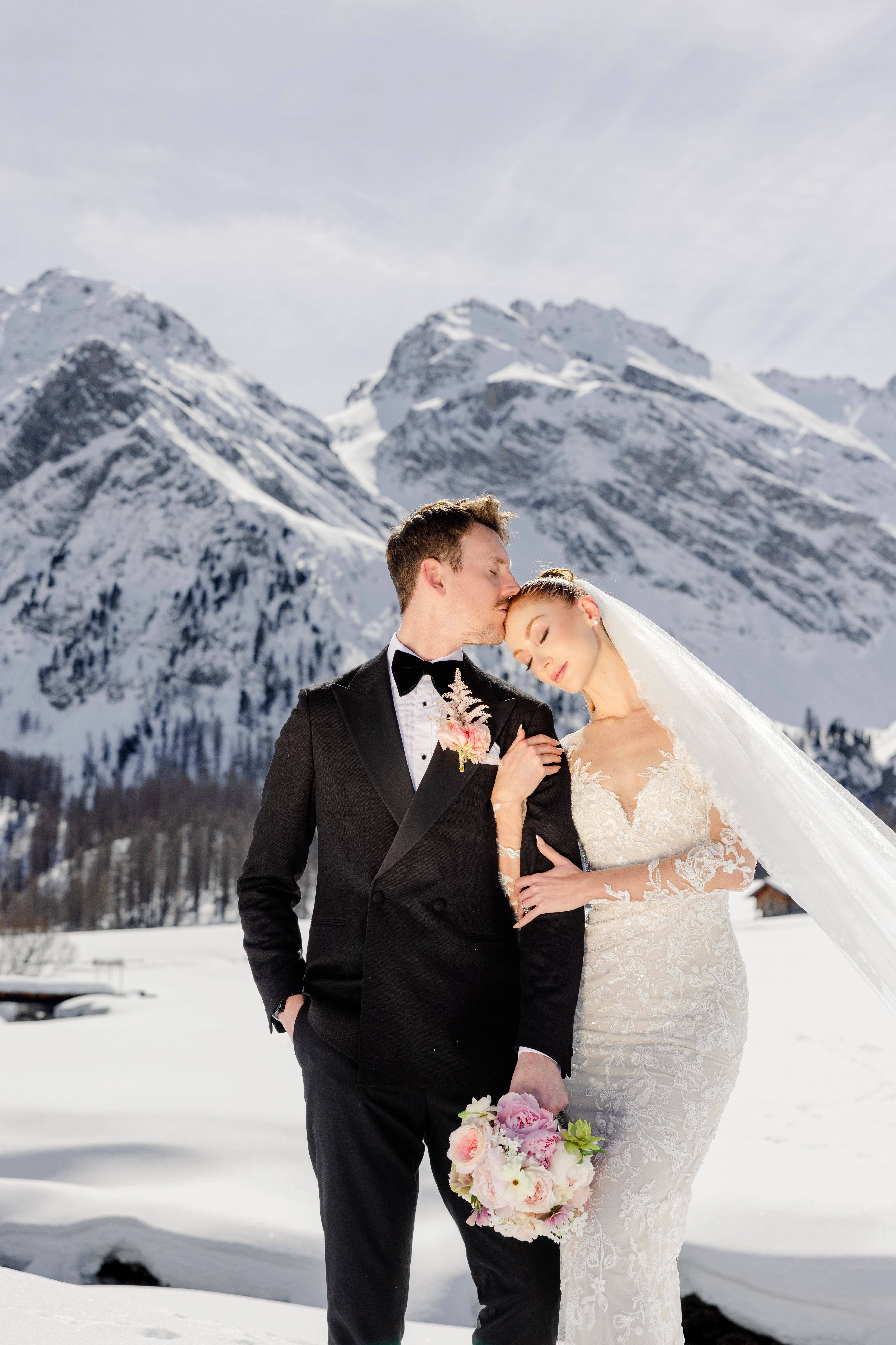 A couple embracing in front of snow-covered mountains.