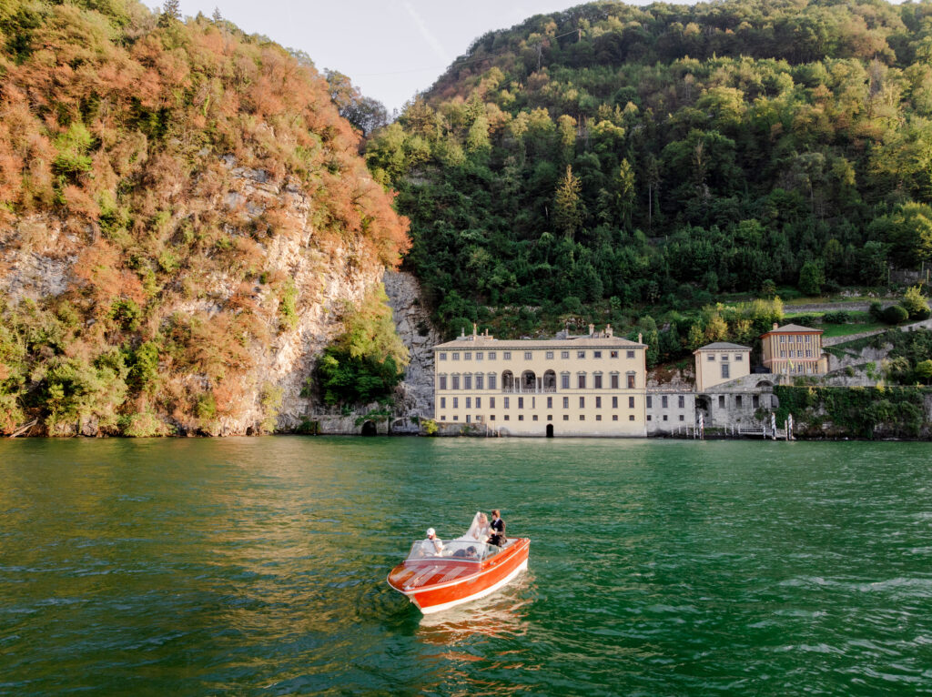 Hochzeitslocation Relais Villa Vittoria am Comer See – Intime Hochzeit in einer historischen Villa 11 Ein Brautpaar in einem Holzboot auf dem See vor dem Relais Villa Vittoria.