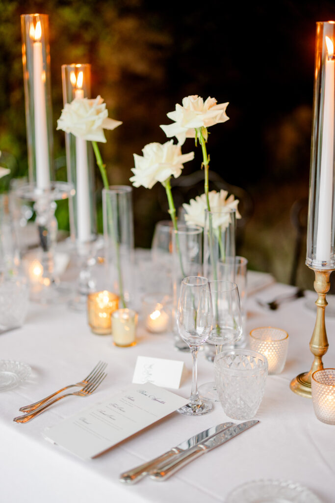Hochzeitslocation Relais Villa Vittoria am Comer See – Intime Hochzeit in einer historischen Villa 12 Ein festlich gedeckter Tisch im Relais Villa Vittoria mit weißen Rosen, hohen Kerzen und Tischkarten.