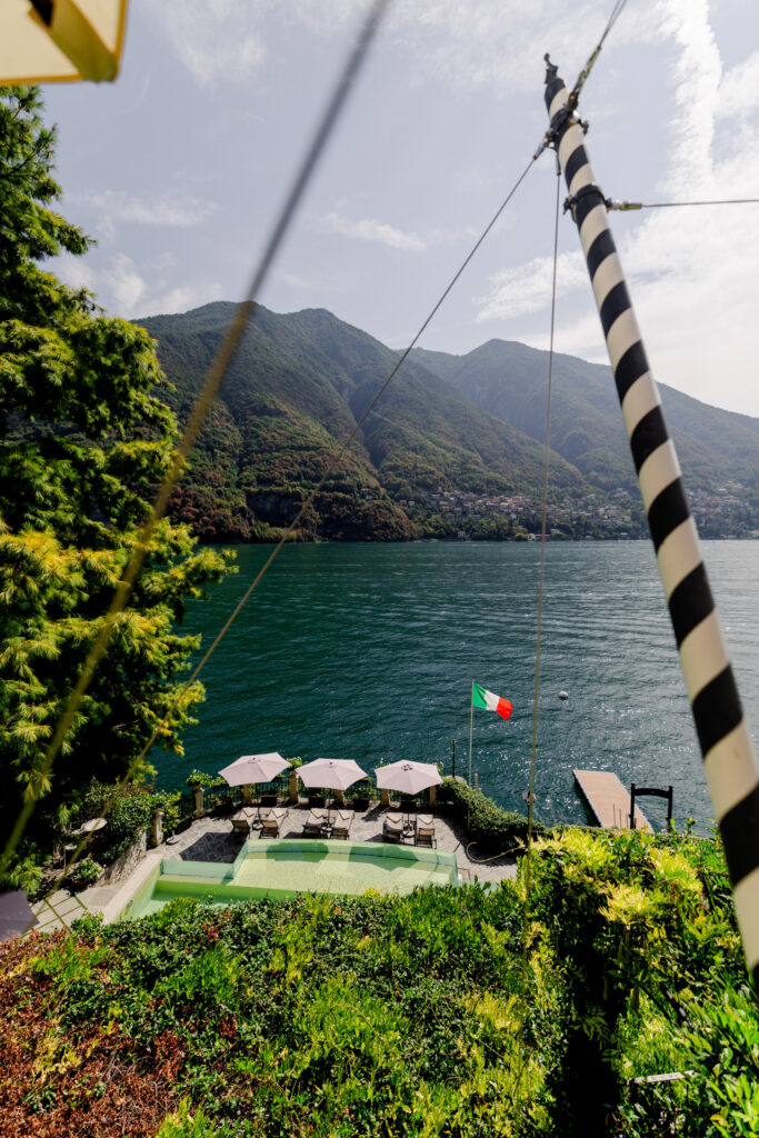 Hochzeitslocation Relais Villa Vittoria am Comer See – Intime Hochzeit in einer historischen Villa 2 Ein Swimmingpool und eine Terrasse mit Sonnenschirmen mit Blick auf einen See und die Berge.